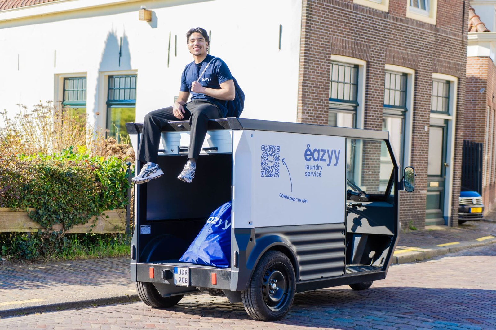 Een eazyy-medewerker bij de bezorgwagen met de blauwe wastas